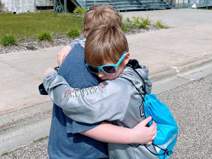 Two brothers embrace in a tight hug while on a walk outside