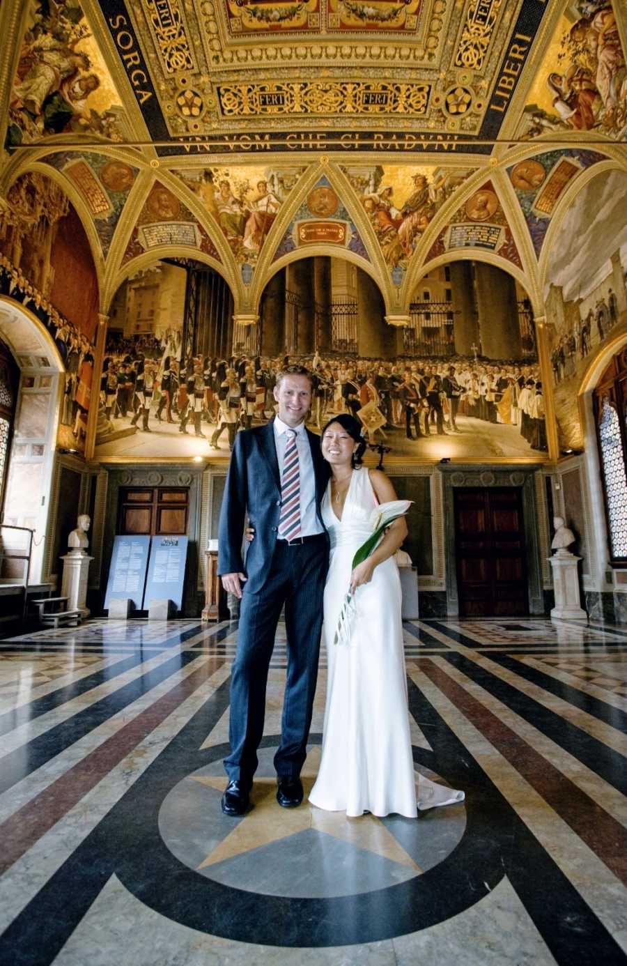 Interracial couple pose for a photo in a cathedral during their wedding