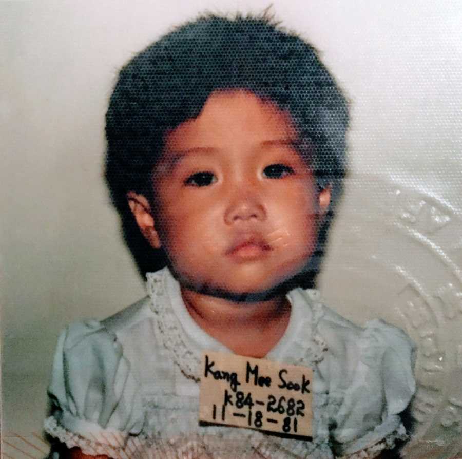 A little girl stares into the camera, expressionless, with a name tag on