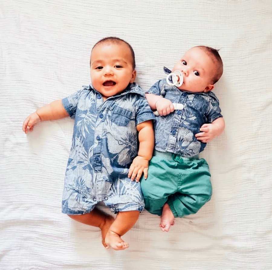 Baby brothers lying down on white blanket