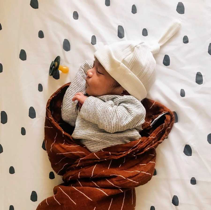 Newborn baby wearing hat swaddled in blanket