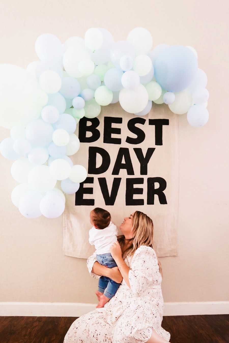 Mom and son standing in front of sign and balloon arch