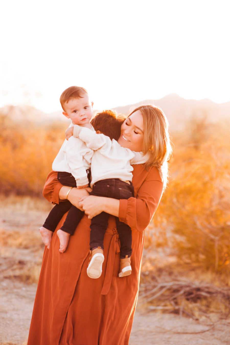 Mother holding two sons posing outside