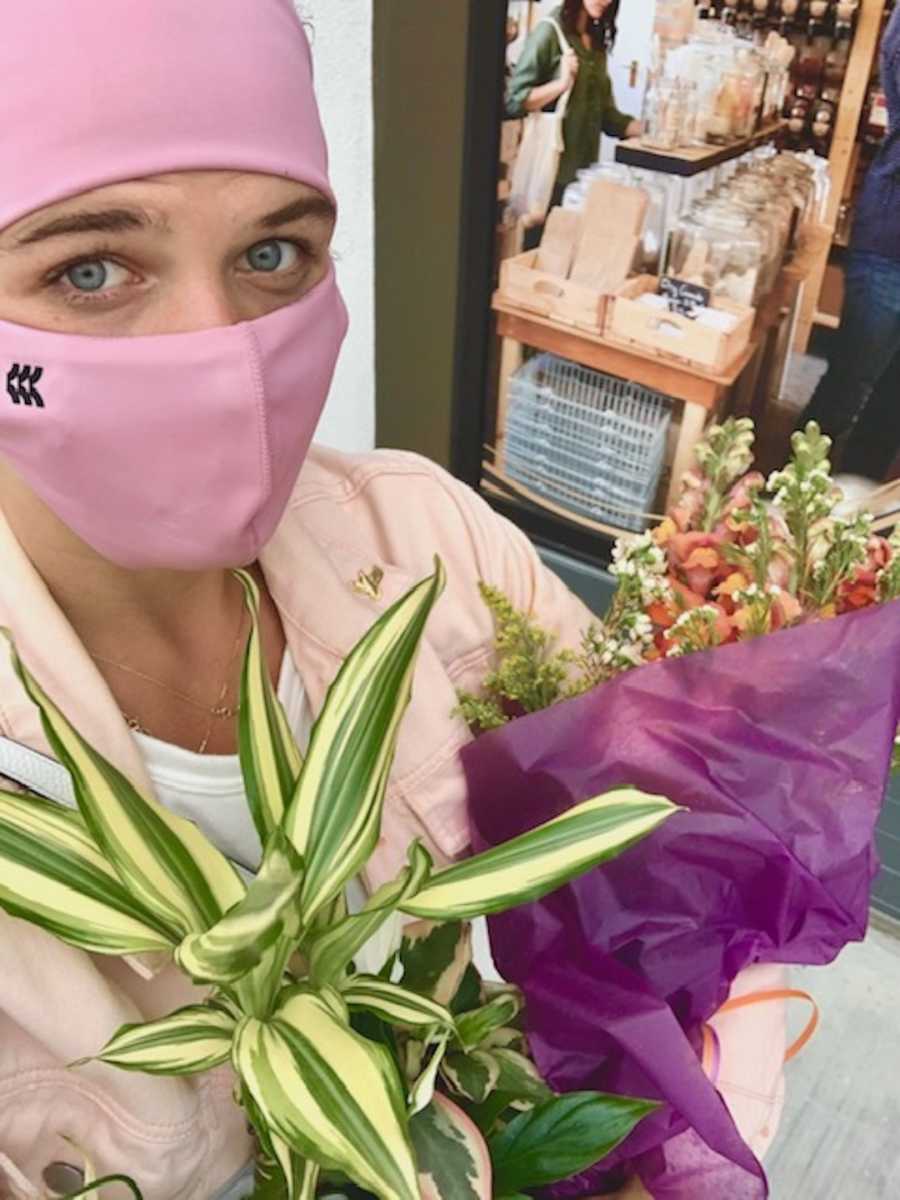 woman in mask holding bouquet of flowers