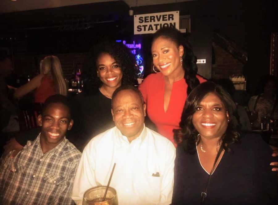 Family of 5 with arms around each other at restaurant smiling