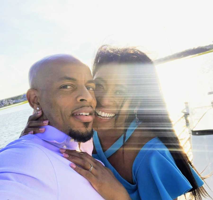 Husband and wife smiling in sunlight on a lake