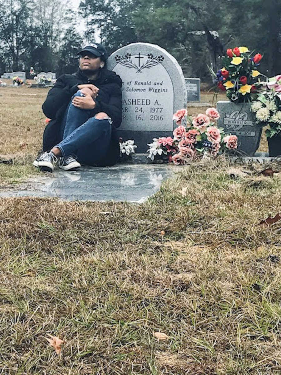 Woman wearing black hat sitting on a gravestone