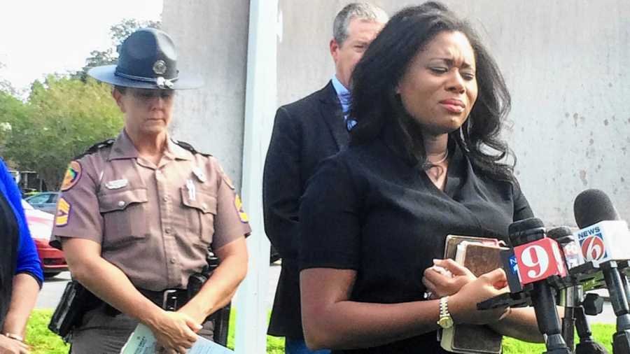 Woman crying and holding Bible at a press conference with sheriff 