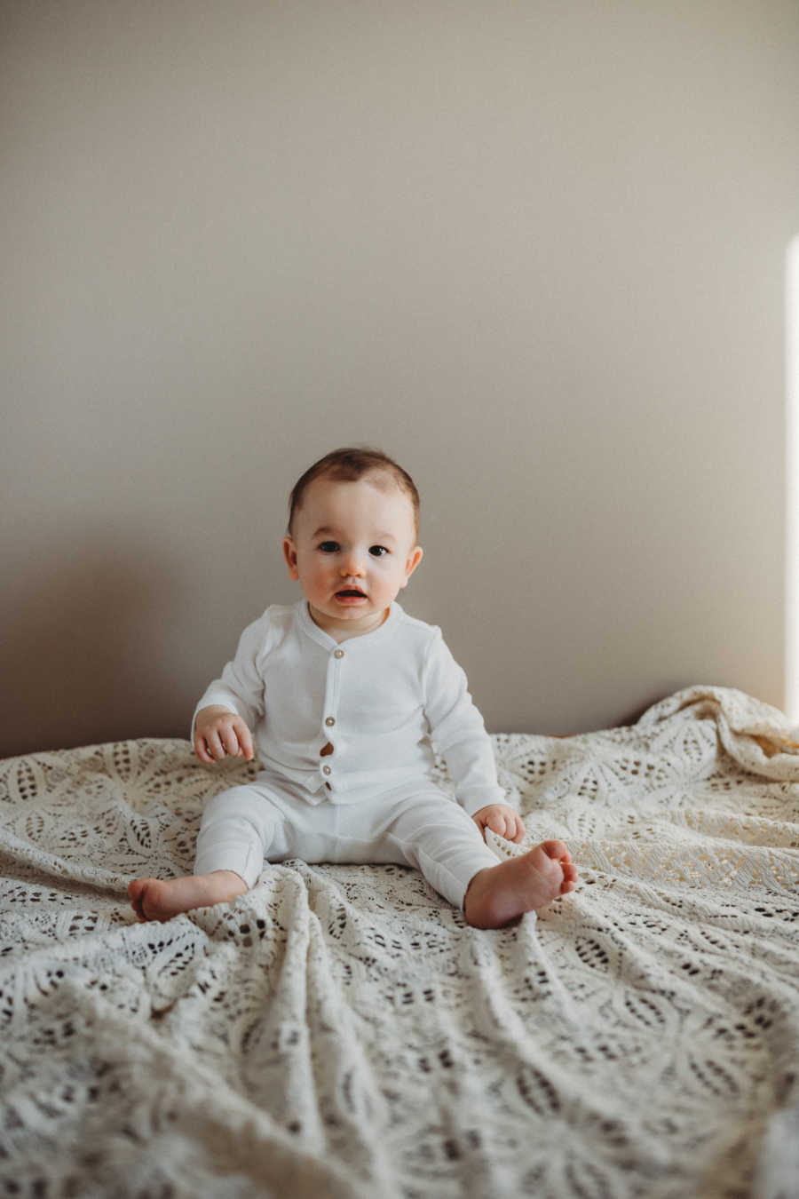 18-month-old baby looks straight at the camera while his mom takes pictures