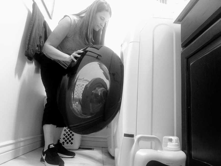 Mom bends down to load the dryer while doing household chores