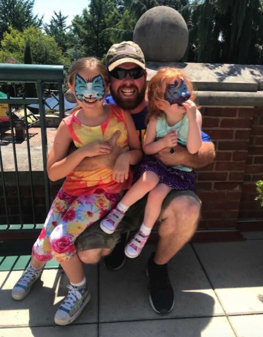 Dad with daughters at theme park with face paint