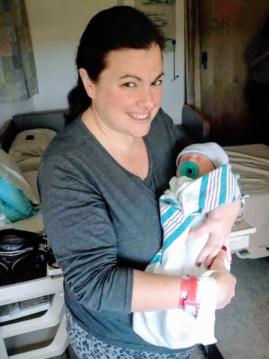 Woman holds her napping son all swaddled up in a blanket