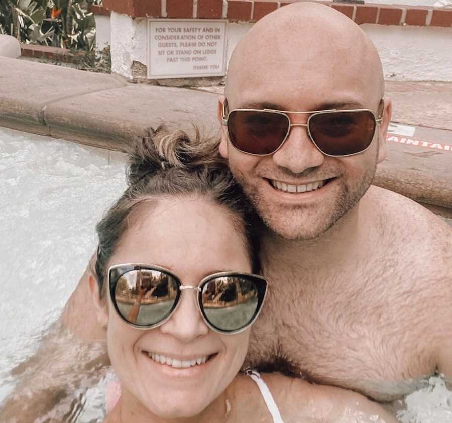 Couple smiling in pool wearing sunglasses