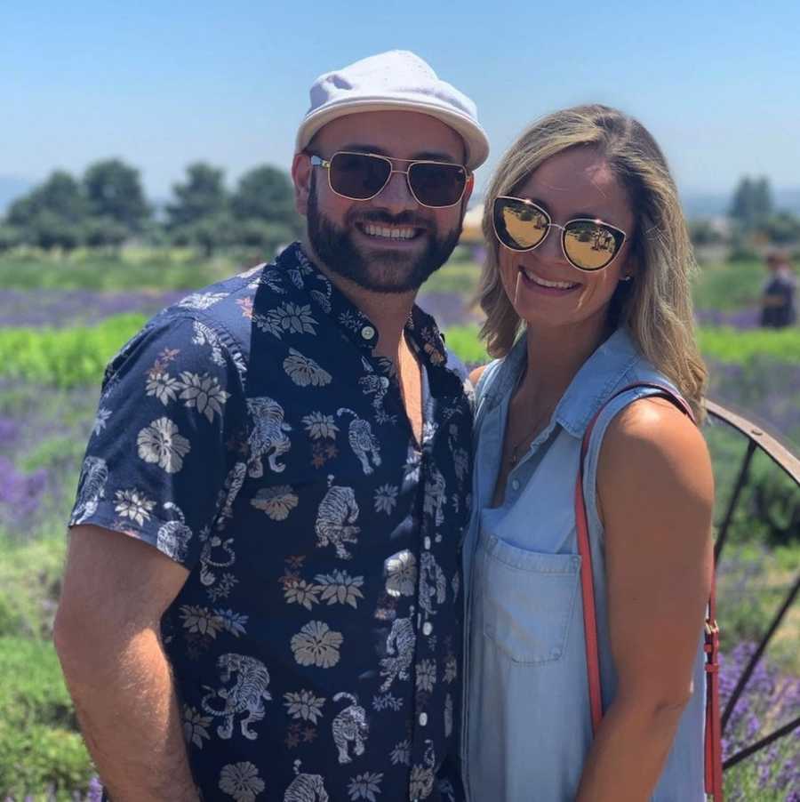 Couple smiling in lavender field wearing sunglasses