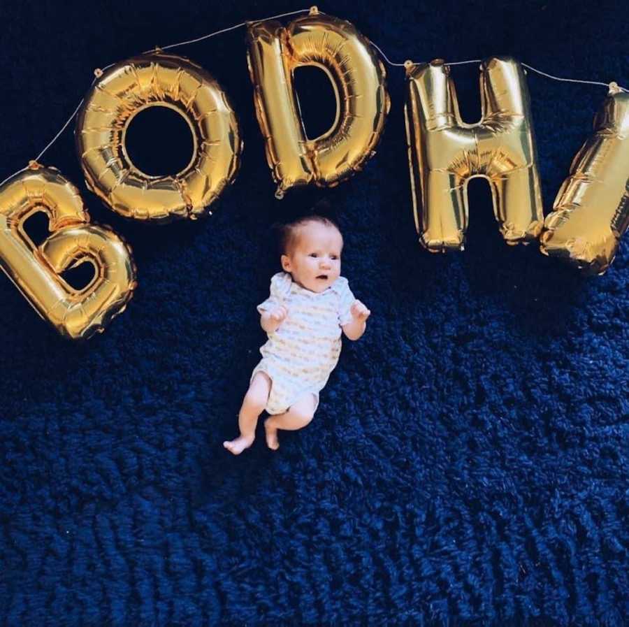 Newborn baby on blue blanket with gold balloons 