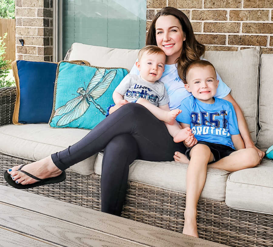 mom holding two sons on couch