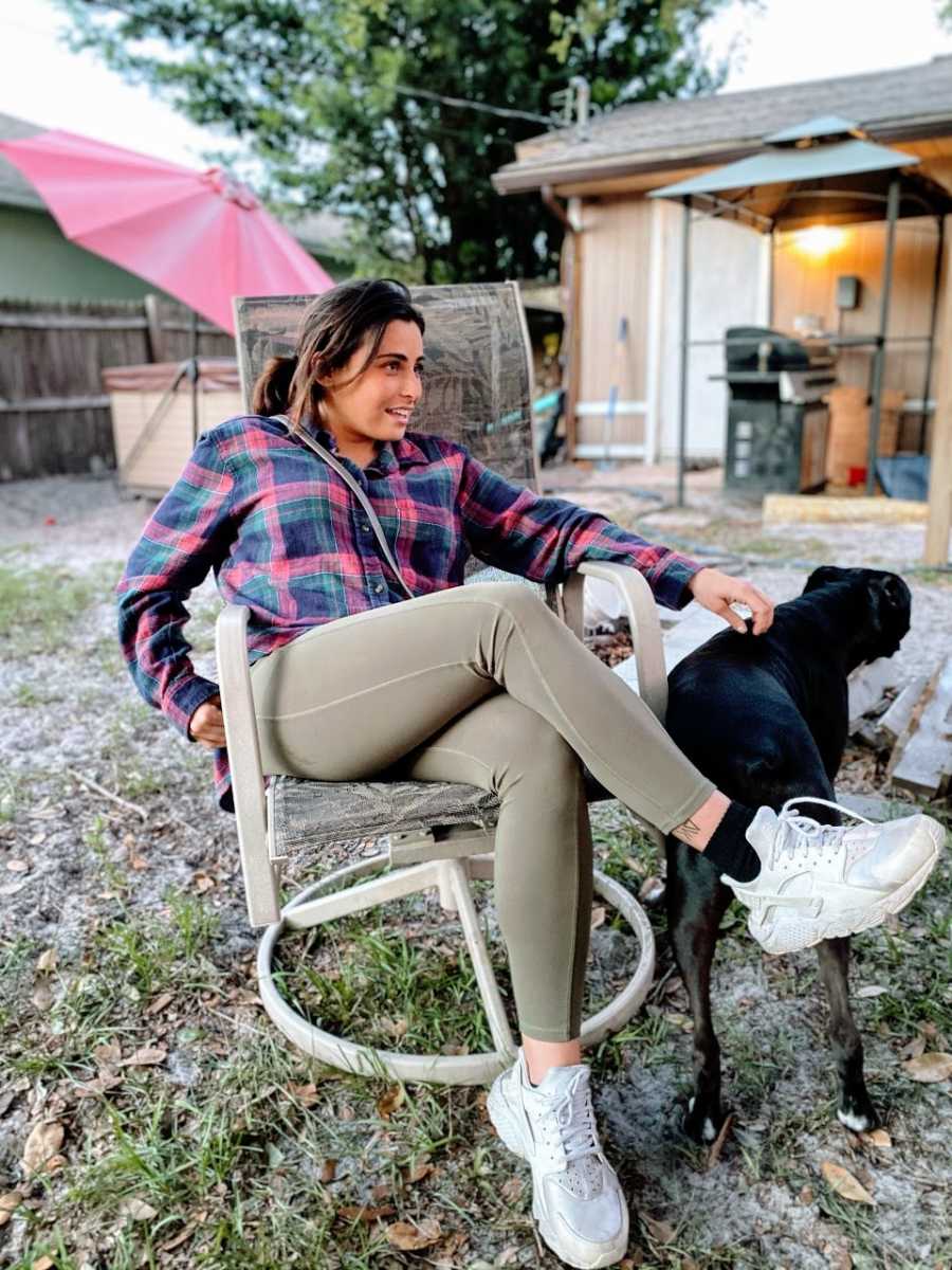 Woman's sister-in-law sits in lawn chair and pets black boxer