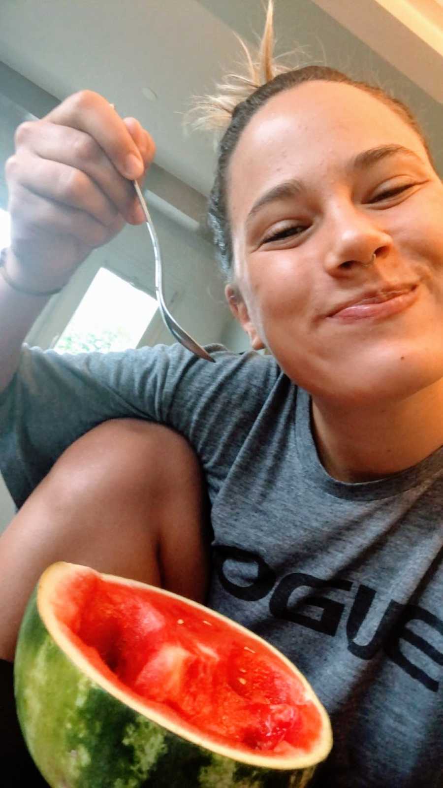 Woman smiles and takes a selfie while eating watermelon as a snack