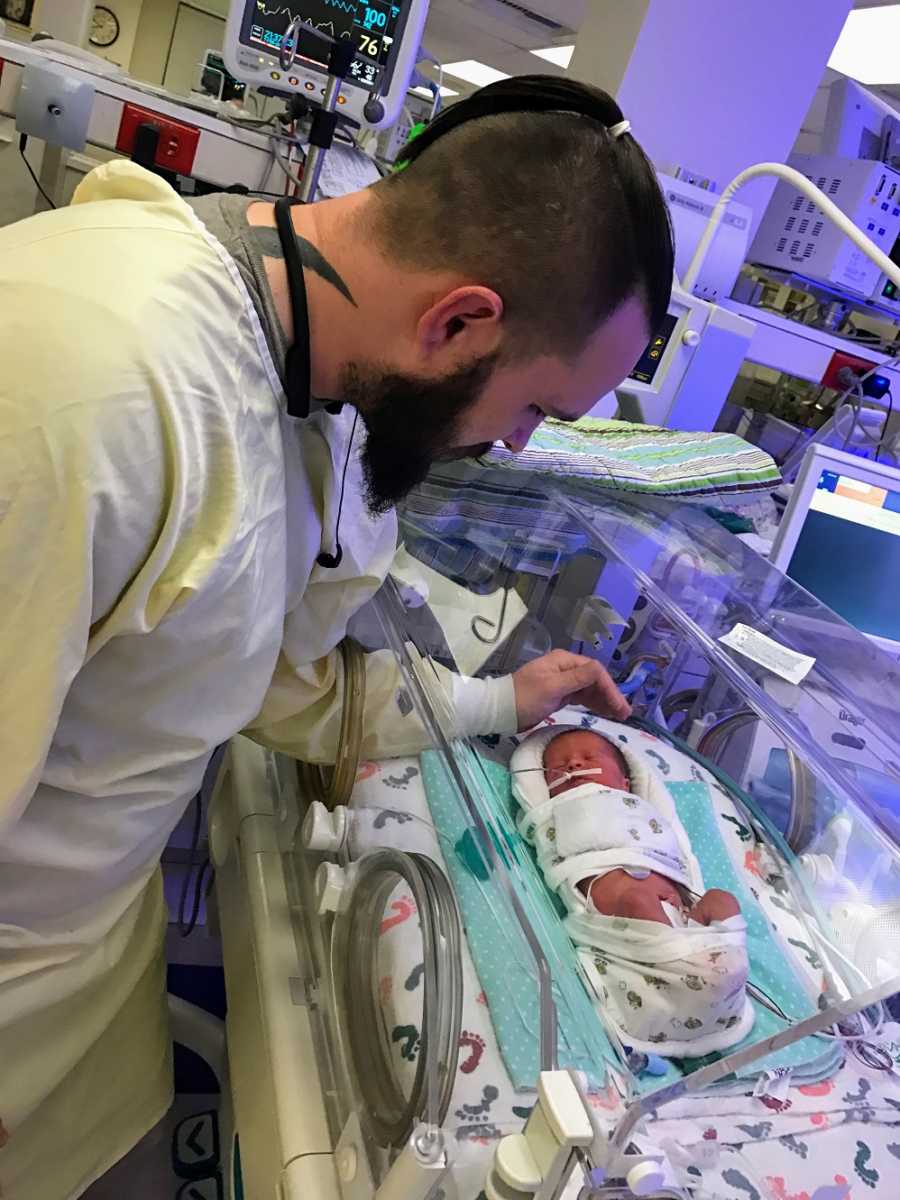 A father checks on his newborn son in the NICU