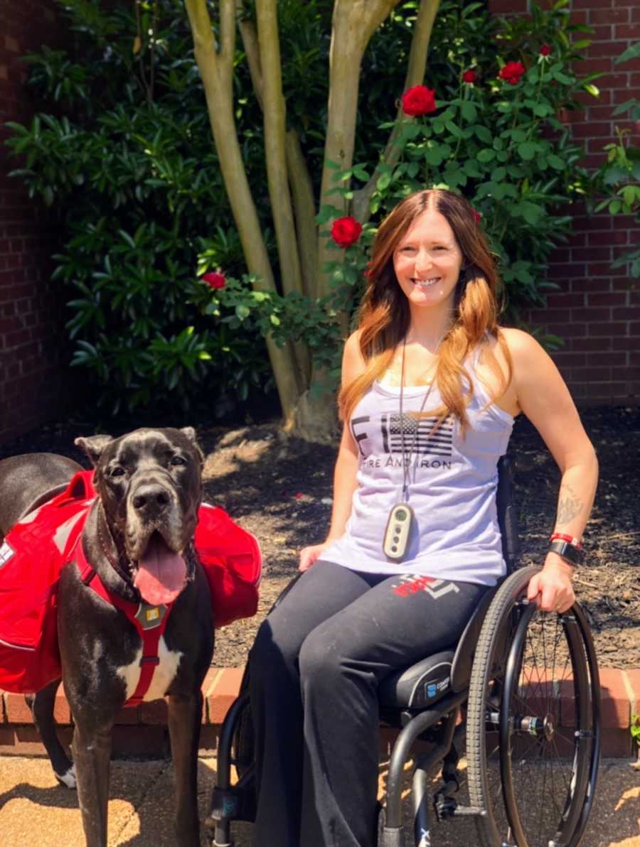 A disabled woman sitting in her wheelchair next to her service dog