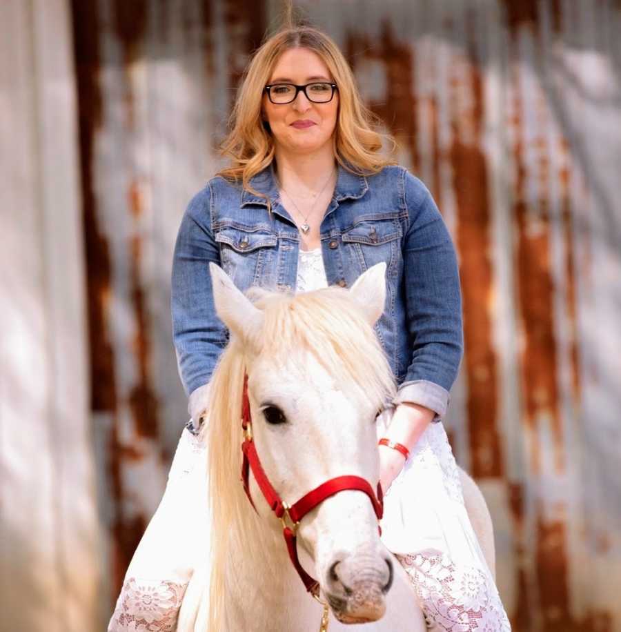 A disabled woman sitting on a white horse