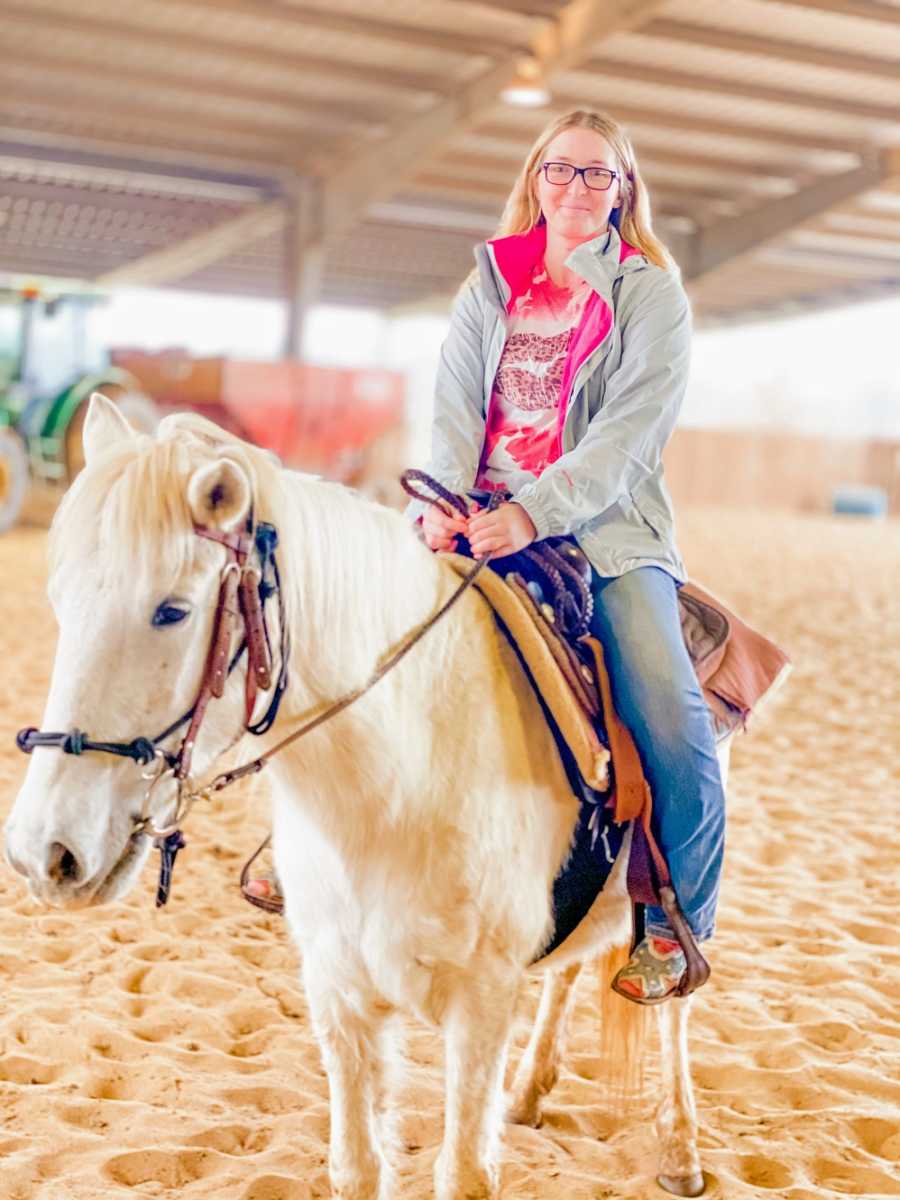 A disabled woman rides a white horse