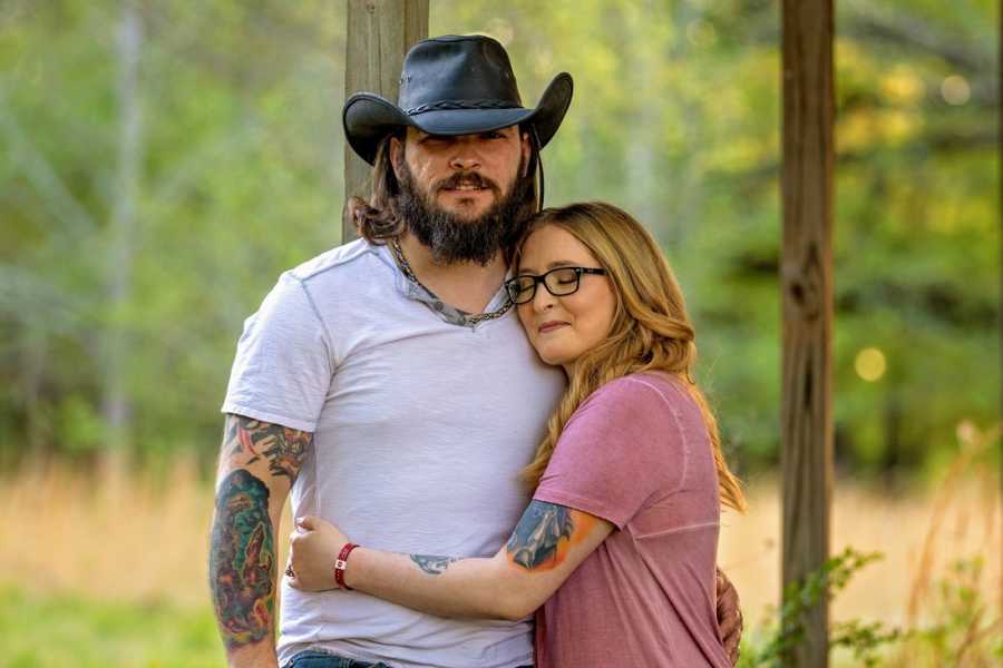 A disabled woman holds her husband for support while they stand for a picture