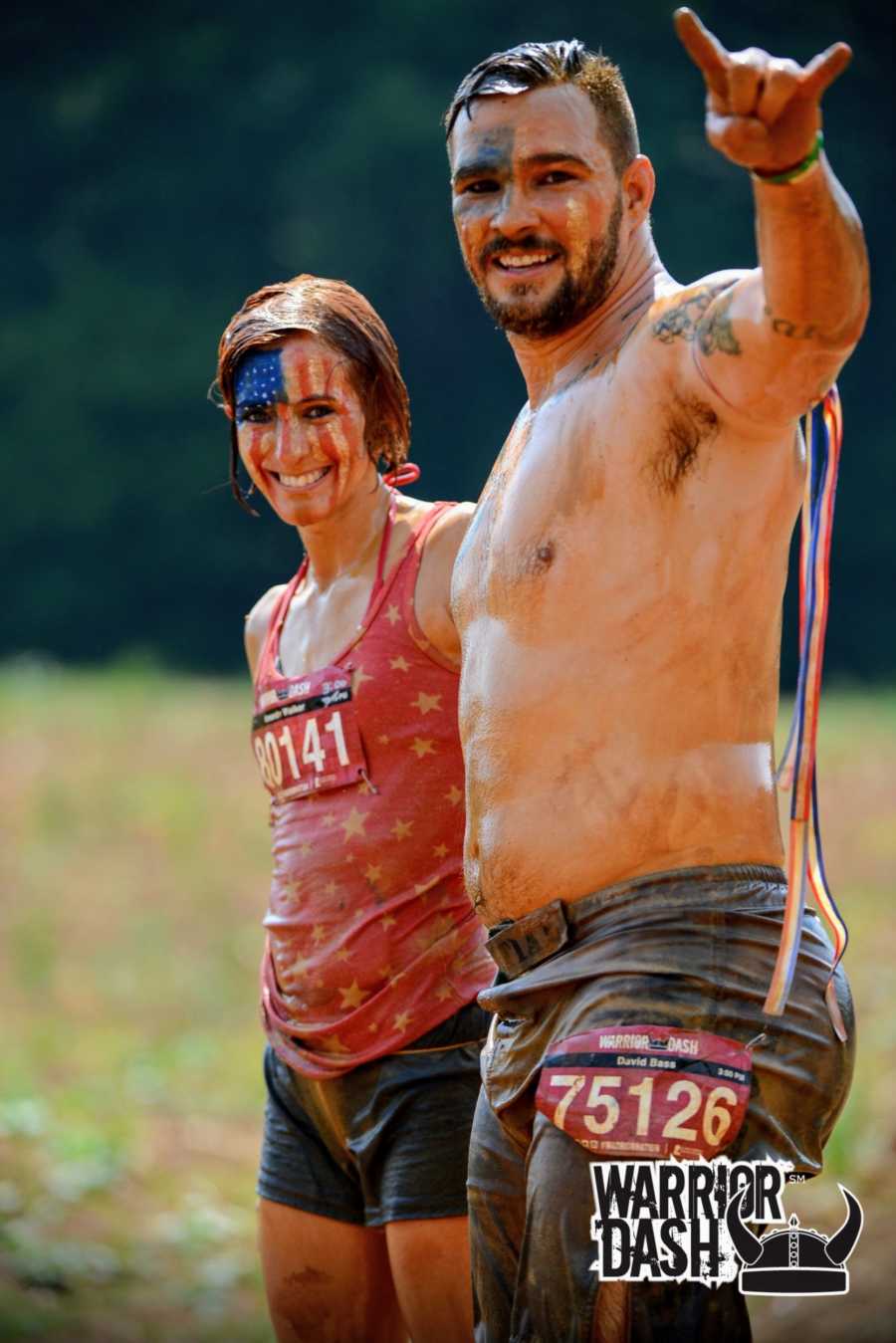 A woman with American flag face paint and her husband stand in muddy clothes