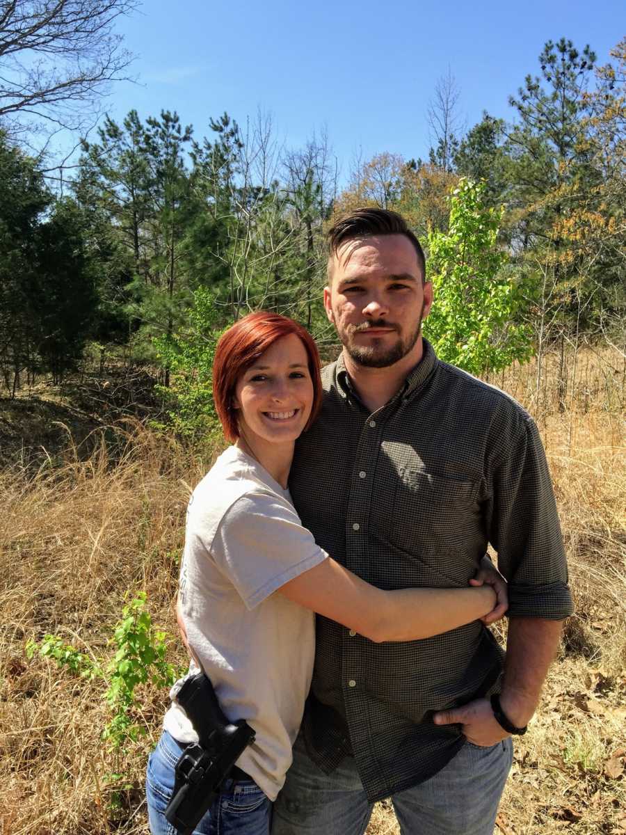 A young husband and wife stand together in a field