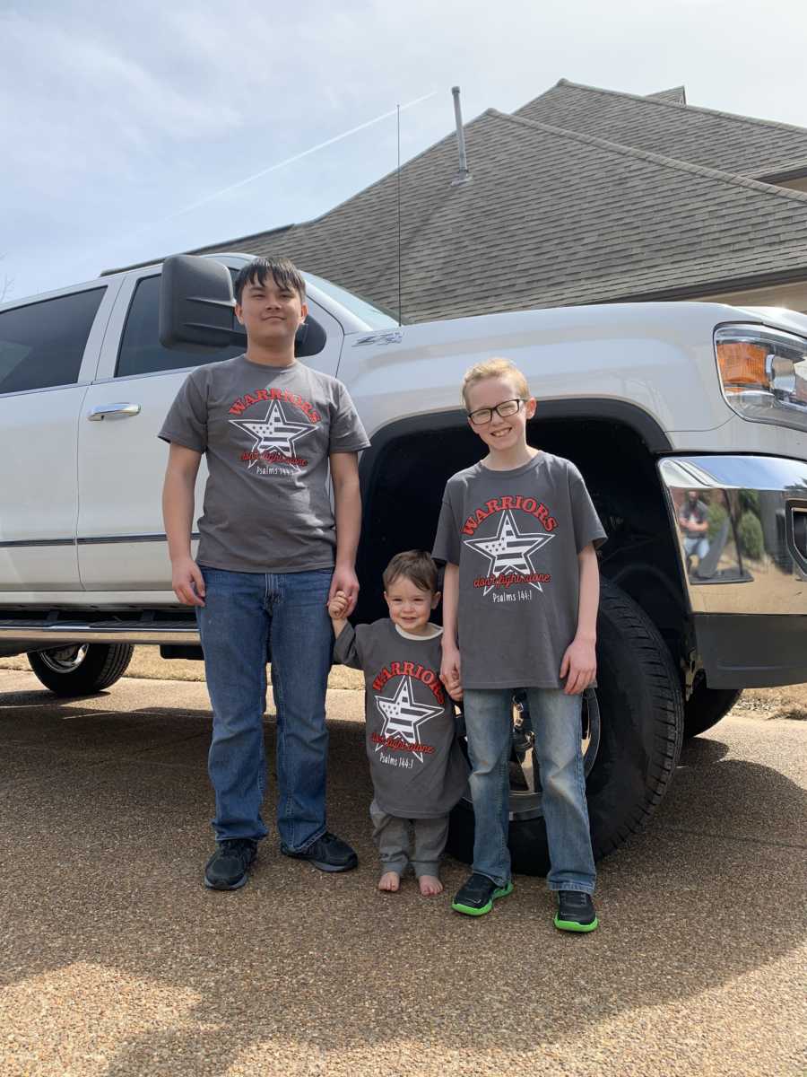 Three brothers stand together next to a truck