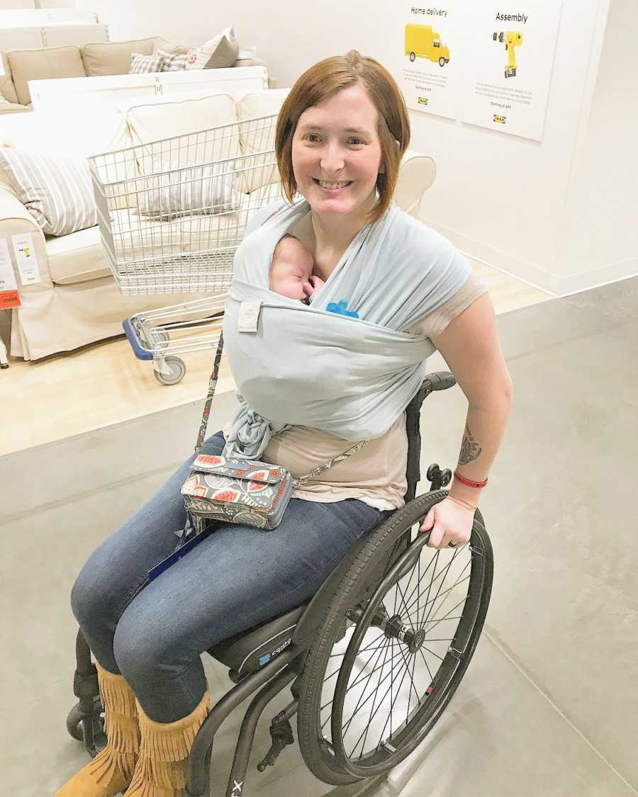 A disabled mother in her wheelchair with her baby wrapped around her chest