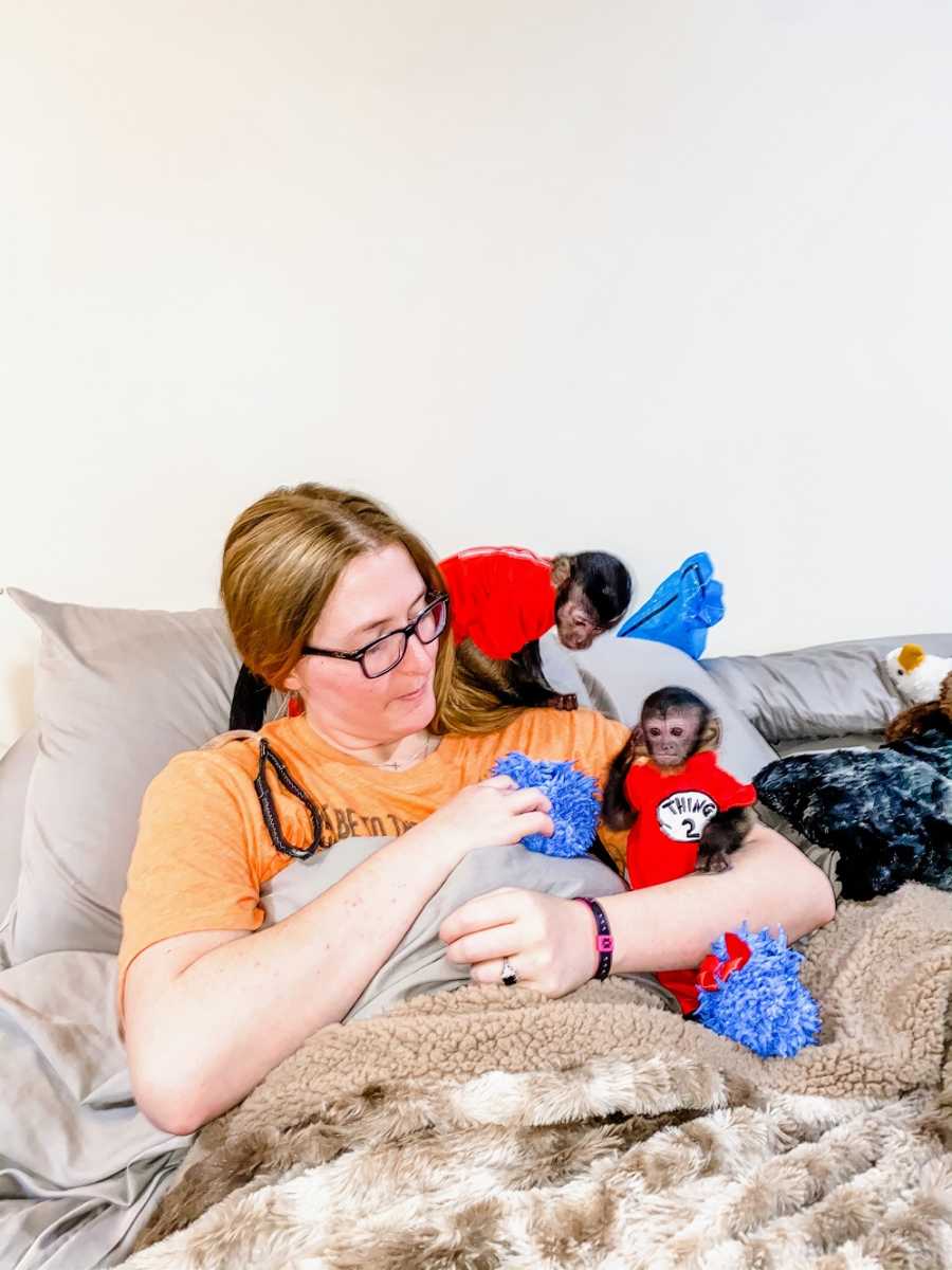 A disabled woman and her two primates sit on a bed