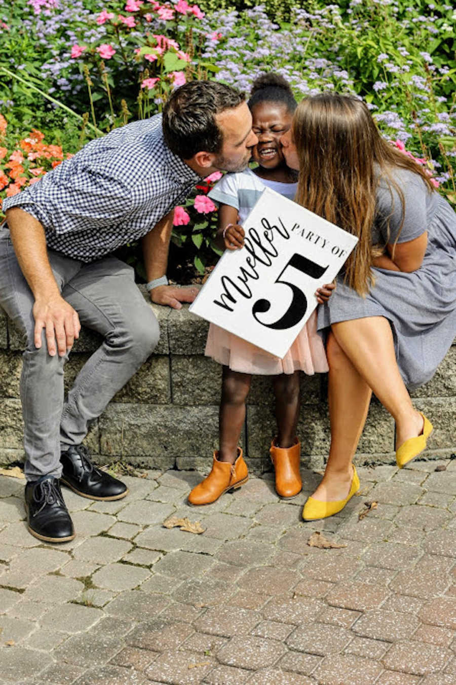 Mother and father kissing newly adopted daughter