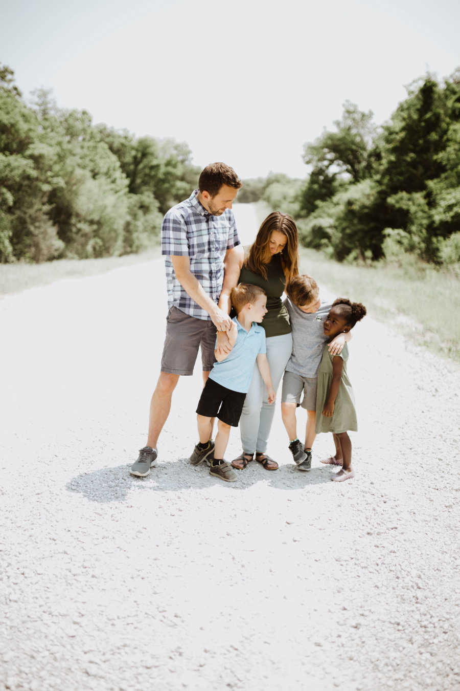 Family of five standing in road smiling at each other