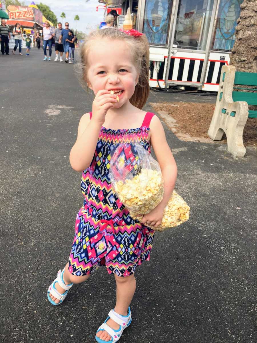 Young girl standing outside holding a bag of popcorn