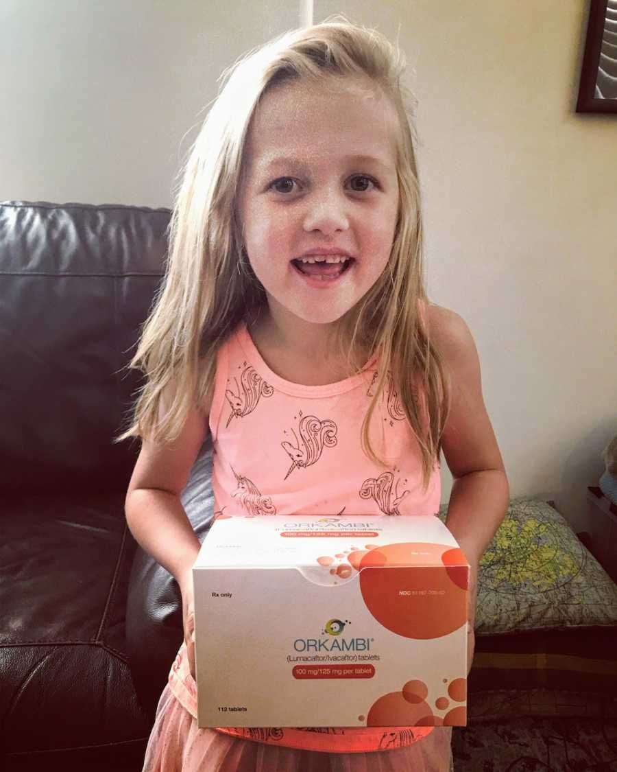 Girl wearing pink shirt holding cystic fibrosis medicine