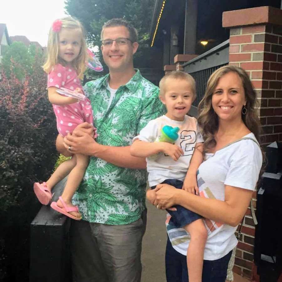 Family of four standing outside of a building and smiling