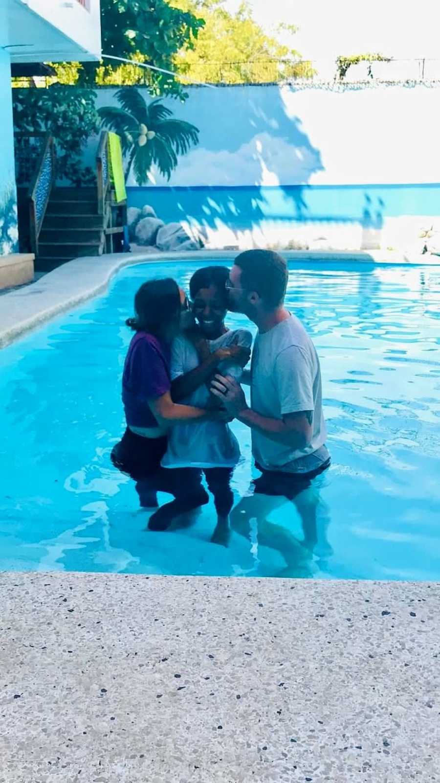 Parents baptising daughter in outside pool