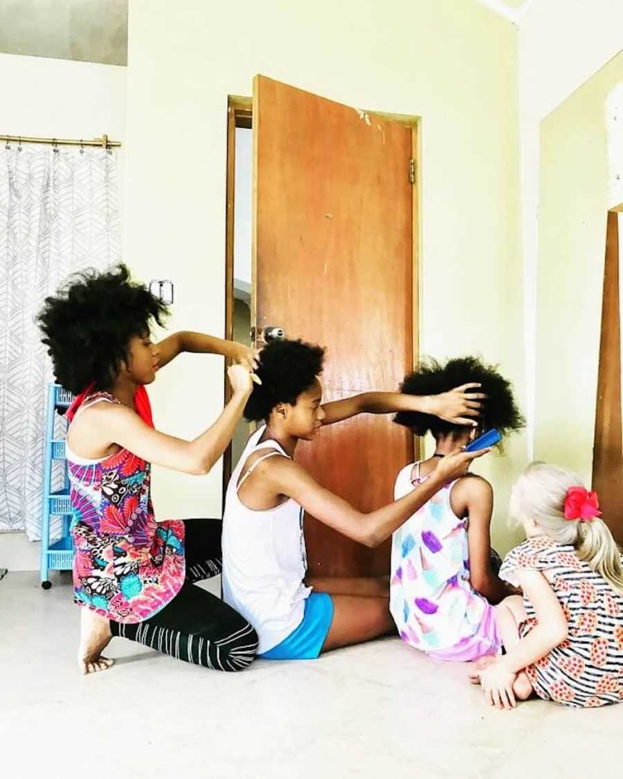 4 siblings doing each other's hair on the floor