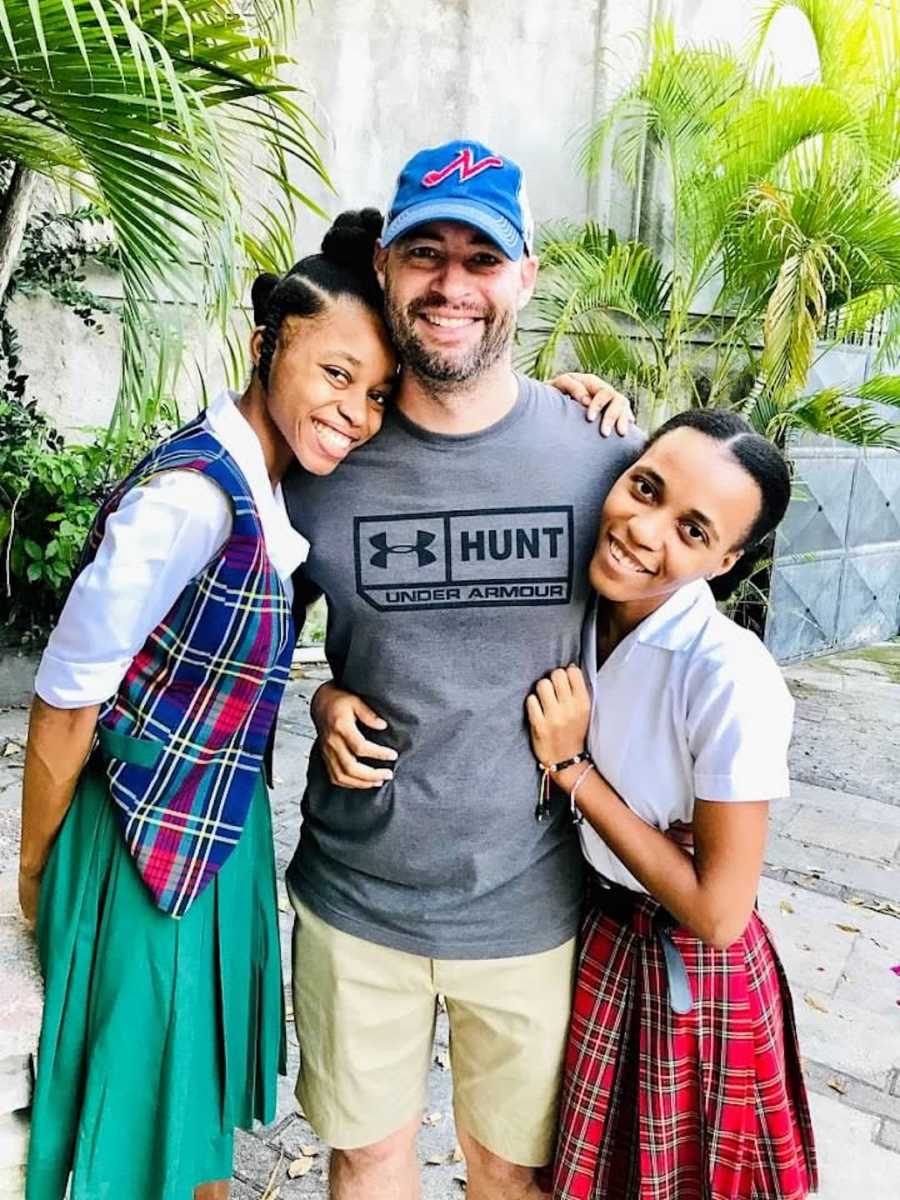 Man smiling with two daughters outside with palm trees