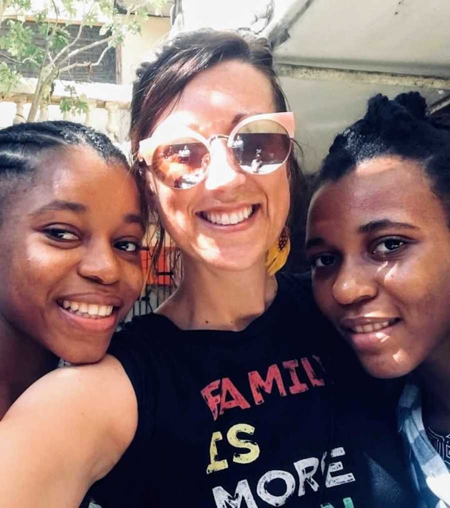 Woman wearing sunglasses smiling with two daughters outside