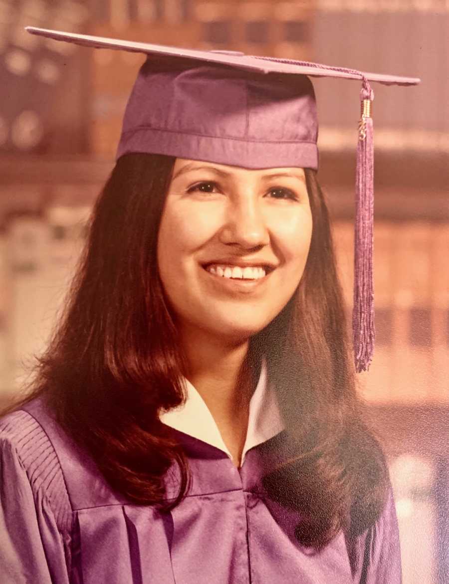 Young woman smiling wearing graduation cap and gown