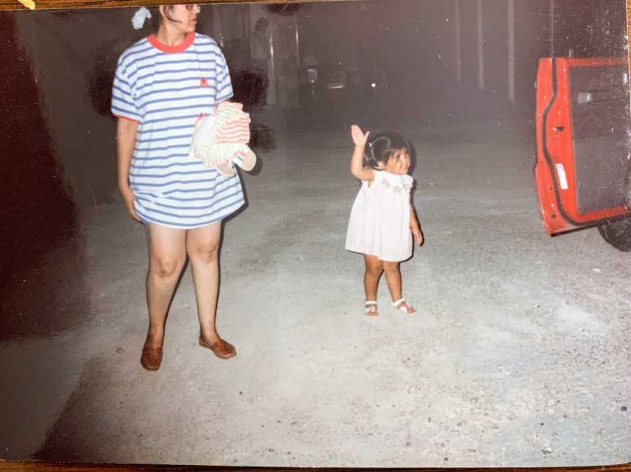 Mother and daughter standing in a garage with a red car