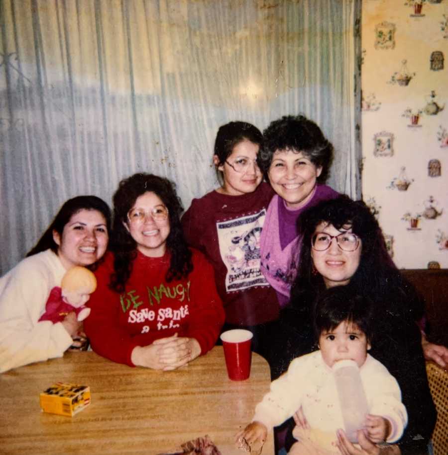 Family photo at a kitchen table with five women and a toddler