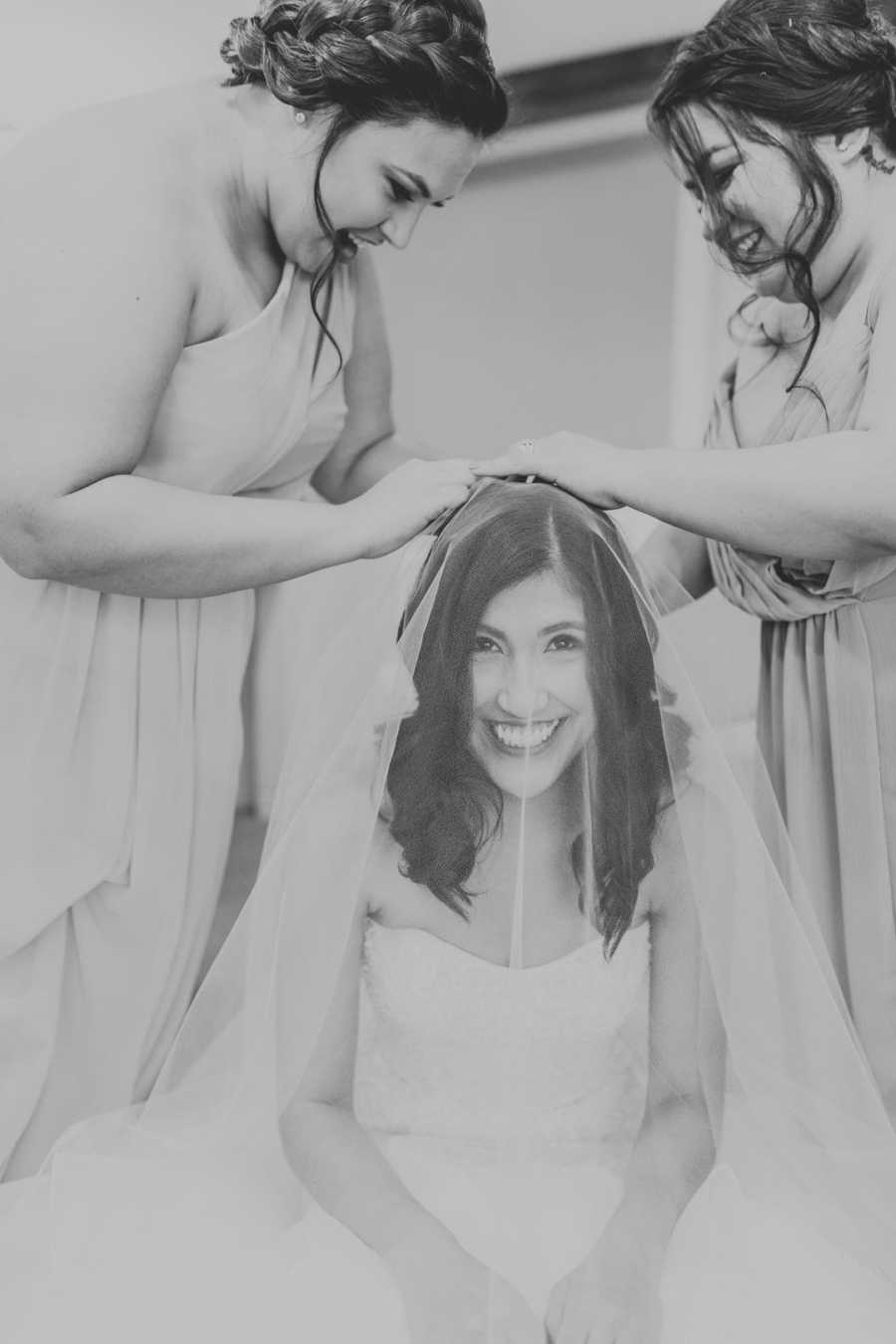 Bride on wedding day getting veil put in by aunts in black and white