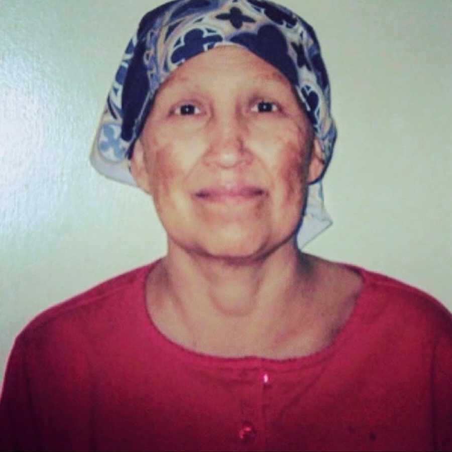 Mother standing in front of white wall wearing a red shirt and bandana