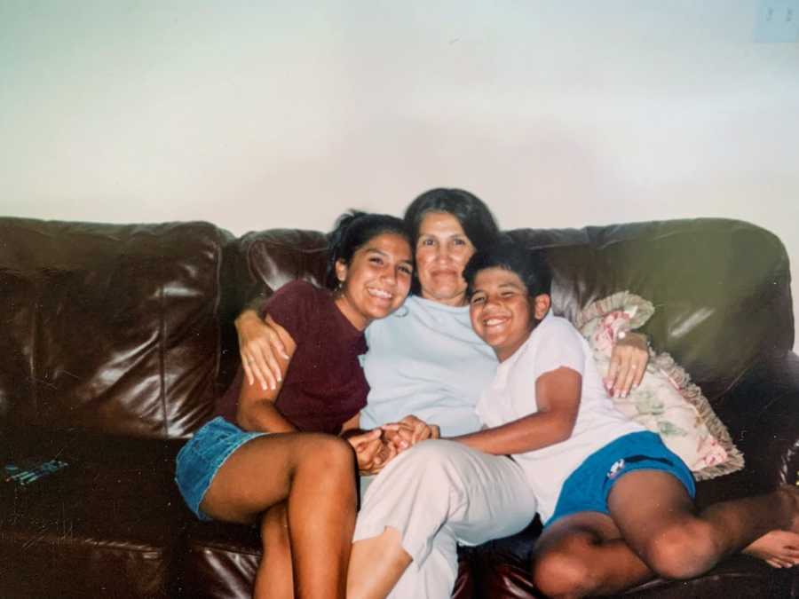 Mother sitting on a couch with her arms around her son and daughter