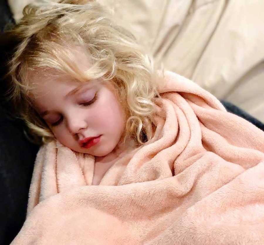 young girl sleeping in a pink blanket