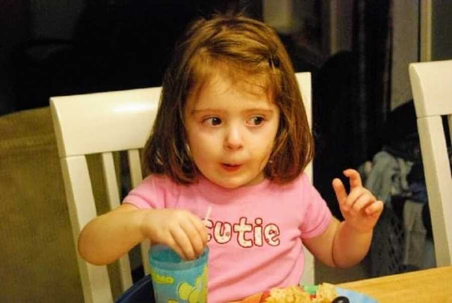 An adopted girl sits at a table to eat