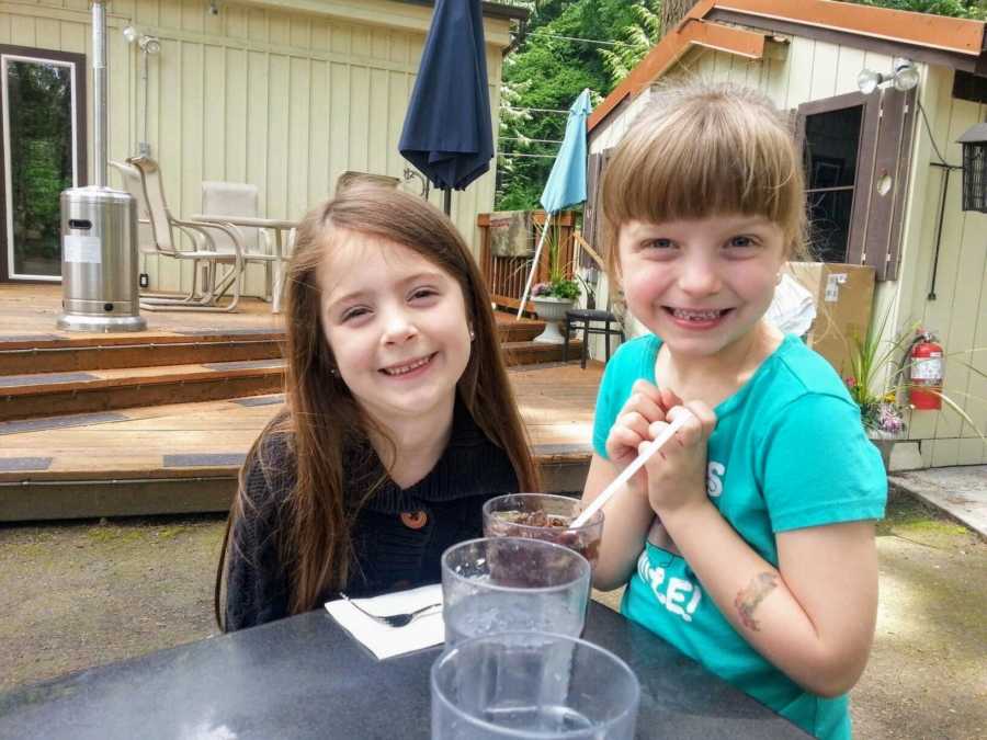 Adoptive sisters sit next to each other at a table